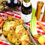 coq a la comtoise på en dukat bord med rutig duk, omringad av primörer och ett glas vin.